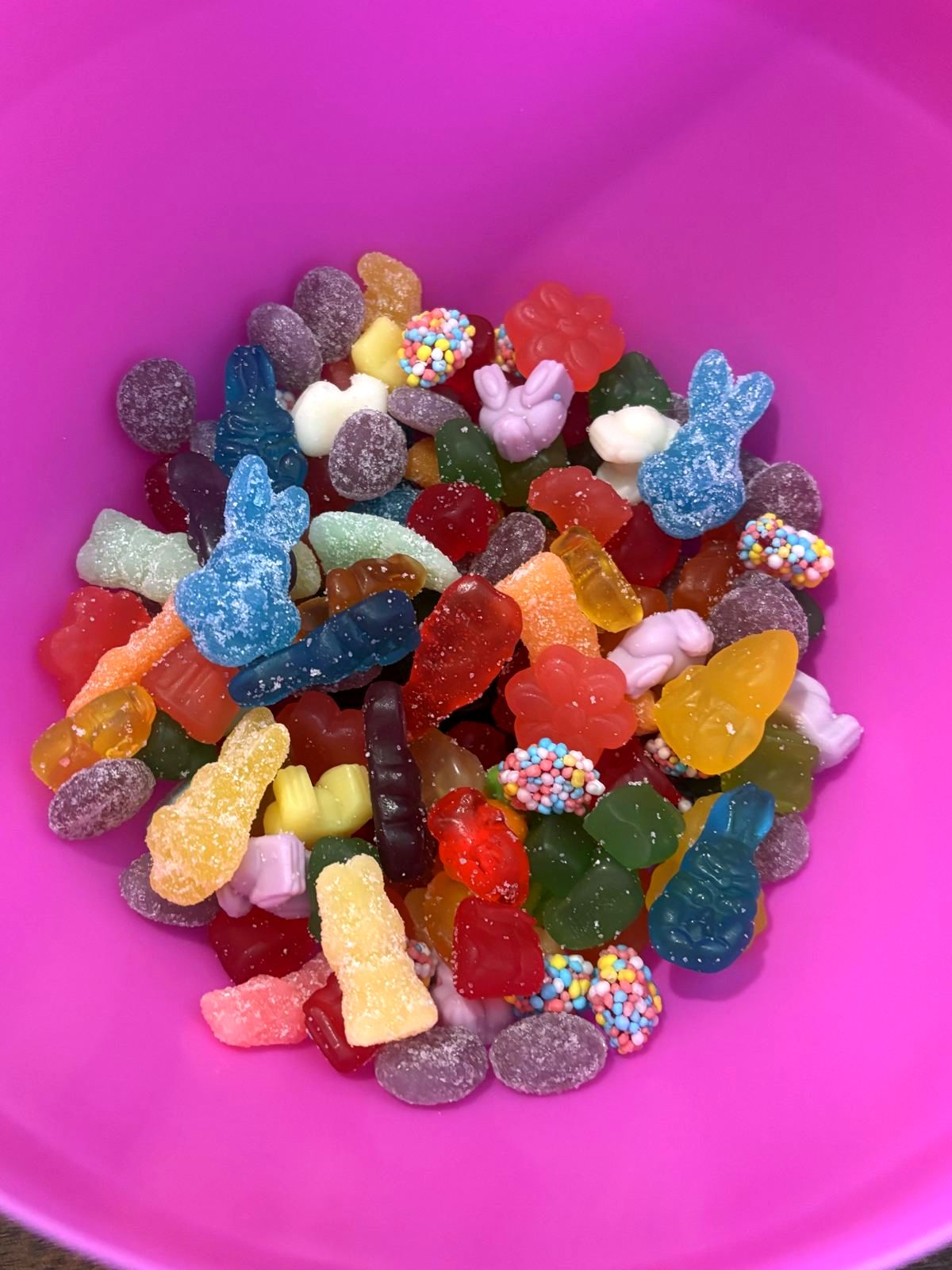 A bright pink bowl filled with pastel Easter gummies